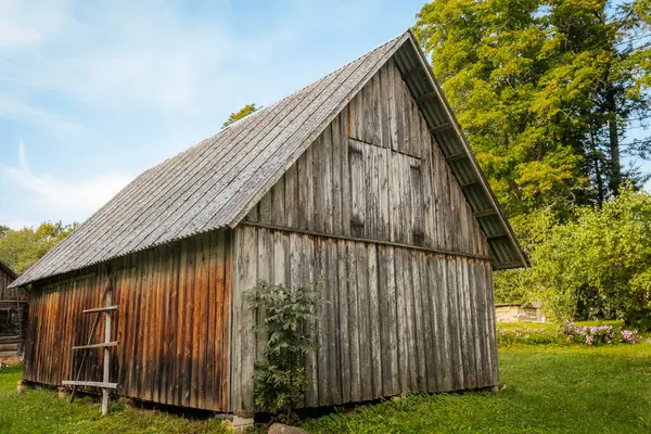 Agricultural building in the countryside with a wooden hut and barn. Rural landscape with a wooden hut in the middle of rural nature. Country hay shed.