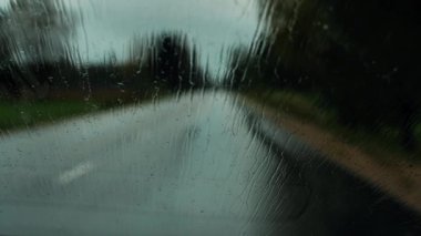 Yağmurlu bir hava. Arabayı yolda sürerken, yağmur arabanın camlarına yağar. Şiddetli yağmur damlaları. Yumuşak seçici odaklanma. Resim için yapay olarak tahıl oluşturuldu.