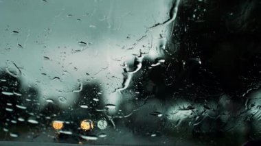 Yağmurlu bir hava. Arabayı yolda sürerken, yağmur arabanın camlarına yağar. Şiddetli yağmur damlaları. Yumuşak seçici odaklanma. Resim için yapay olarak tahıl oluşturuldu.