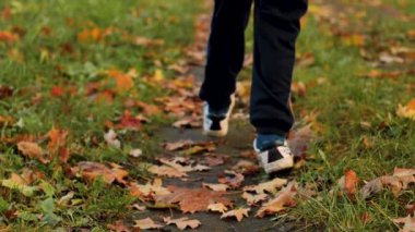 Bir çocuk sonbahar yaprakları arasında koşar. Sonbahar yapraklı patika. Yumuşak seçici odak.