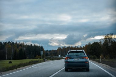 Stormy Sky Hava Yolunda Araba Turu. Mavi bir araba fırtınalı bir gökyüzünün altında otobanda ilerliyor. Yumuşak seçici odak. 
