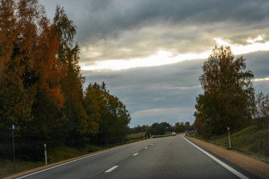 Stormy Sky Hava Yolunda Araba Turu. Mavi bir araba fırtınalı bir gökyüzünün altında otobanda ilerliyor. Yumuşak seçici odak. 