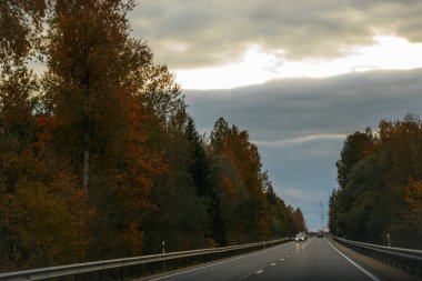 Stormy Sky Hava Yolunda Araba Turu. Mavi bir araba fırtınalı bir gökyüzünün altında otobanda ilerliyor. Yumuşak seçici odak. 