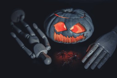 Cadılar Bayramı tavanında örümcekler ve ahşap elli ahşap adam. Minimum aydınlatma. Siyah arka plan. Parlak, renkli turuncu bir nesne, sade siyah bir zemin üzerinde, minimum ışıklandırmayla..