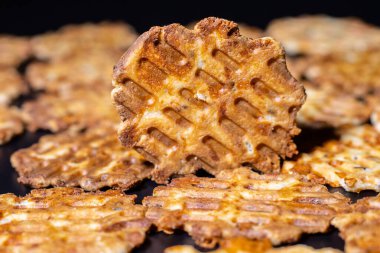 Lezzetli bir kahvaltı tabağı, kızarmış peynirli waffle. Tabaktaki lezzetli, ısırık büyüklüğünde atıştırmalıkların yakın çekimi. Siyah arka planda fırında peynirli waffle..
