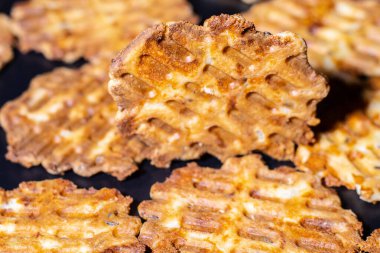 Lezzetli bir kahvaltı tabağı, kızarmış peynirli waffle. Tabaktaki lezzetli, ısırık büyüklüğünde atıştırmalıkların yakın çekimi. Siyah arka planda fırında peynirli waffle..
