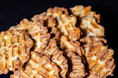 Lezzetli bir kahvaltı tabağı, kızarmış peynirli waffle. Tabaktaki lezzetli, ısırık büyüklüğünde atıştırmalıkların yakın çekimi. Siyah arka planda fırında peynirli waffle..