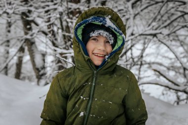 Kar yığınının içinde bir çocuk. Karda yatan biri kar meleği yapar. Karlı bir arazide kar meleği yapan bir adam.