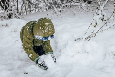 Kar yığınının içinde bir çocuk. Karda yatan biri kar meleği yapar. Karlı bir arazide kar meleği yapan bir adam.