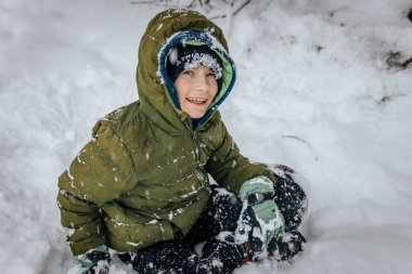 Kar yığınının içinde bir çocuk. Karda yatan biri kar meleği yapar. Karlı bir arazide kar meleği yapan bir adam.