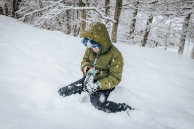 Kar yığınının içinde bir çocuk. Karda yatan biri kar meleği yapar. Karlı bir arazide kar meleği yapan bir adam.