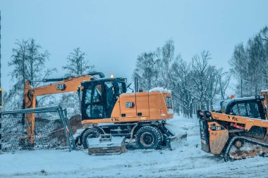 Karlı kış manzarasında yolu tamir eden bir grup insan. Bir grup insan kışın karlı havada traktörle toprağı kazıyor. Çoğunlukla seçici bir odak noktası.. 