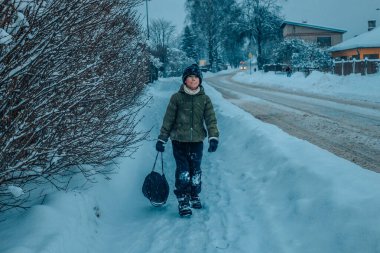 Sıcak kış giysileri içinde bir adam karlı bir ağacın önünde duruyor. Karlı bir yolda kalın kışlık giysiler giyen biri. Çocuk karla kaplı..
