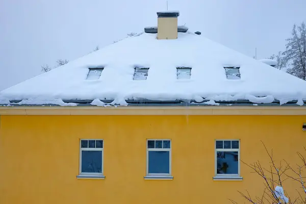 Sarı okul binası. Şehrin yerleşim bölgesinde kış camı cephede. Karlı konut binaları ve buzlu pencereleri olan kış şehirleri.