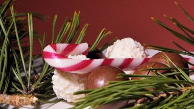 Çikolata ve hindistan cevizli Noel topları. Masada şekerler dönüyor. Dekorasyon için çam iğneleri. Video klipler. Yumuşak seçici odaklanma. Resim için yapay olarak tahıl oluşturuldu