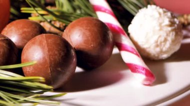 Çikolata ve hindistan cevizli Noel topları. Masada şekerler dönüyor. Dekorasyon için çam iğneleri. Video klipler. Yumuşak seçici odaklanma. Resim için yapay olarak tahıl oluşturuldu