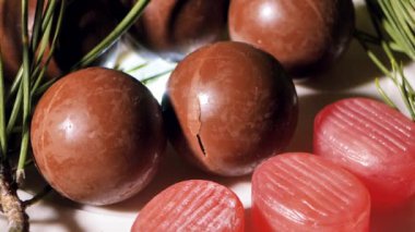 Çikolata ve hindistan cevizli Noel topları. Masada şekerler dönüyor. Dekorasyon için çam iğneleri. Video klipler. Yumuşak seçici odaklanma. Resim için yapay olarak tahıl oluşturuldu