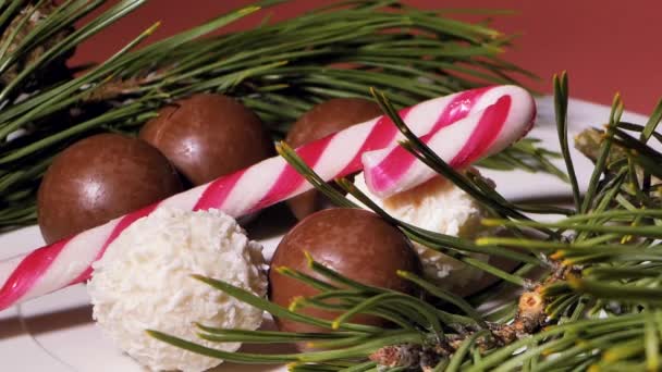 チョコレートとココナッツのクリスマスボール キャンディーはテーブルの上に回っています 装飾のためのパイン針 ビデオクリップ 柔らかい選択的な焦点 写真のための人工的に作られた穀物 — ストック動画