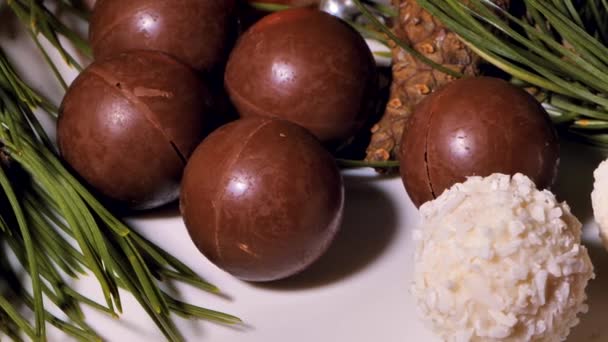 チョコレートとココナッツのクリスマスボール キャンディーはテーブルの上に回っています 装飾のためのパイン針 ビデオクリップ 柔らかい選択的な焦点 写真のための人工的に作られた穀物 — ストック動画