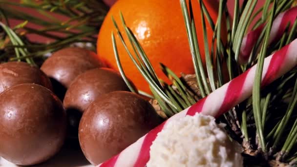 초콜릿과 코코넛 크리스마스 사탕이 테이블에 회전하고 있습니다 탱저린스 장식을위한 소나무 — 비디오