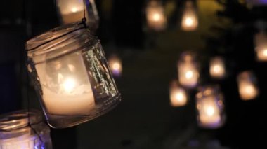 Noel ışıkları parlıyor ve kar yağıyor. Cam bir kavanozda tatil süsleme mumu. Videolar. Yumuşak seçici odaklanma. Yapay olarak oluşturulan tahıllar.