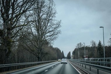 Bahar döneminde araba trafiği olan Valmiera Riga yolu. Ana caddelerdeki Riga binaları. 