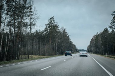 Bahar döneminde araba trafiği olan Valmiera Riga yolu. Ana caddelerdeki Riga binaları. 