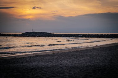 Parlak maviler, portakallar ve sarılarla çarpıcı bir günbatımı gökyüzü. Işık bulutları ufukta parlak desenler oluşturur..