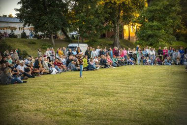 Neşeli bir topluluk güneşli bir günde ferah bir parkta toplanır. İnsanlar yeşil çimlere dağılmış, bazıları köpeklerini gezdiriyor, sosyalleşiyorlar ve dışarıda eğleniyorlar.. 