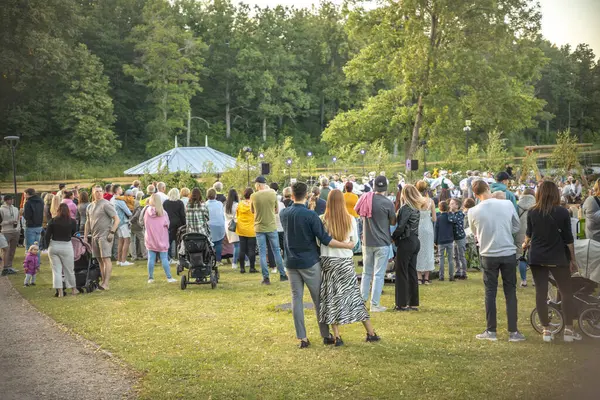 Neşeli bir topluluk güneşli bir günde ferah bir parkta toplanır. İnsanlar yeşil çimlere dağılmış, bazıları köpeklerini gezdiriyor, sosyalleşiyorlar ve dışarıda eğleniyorlar.. 