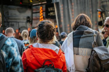 Çeşitli bir grup insan, festivalde birbirlerine yakın durup dikkatle izlediler.