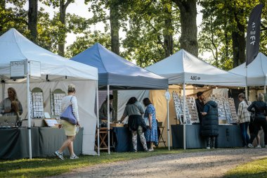 Bir grup insan açık hava etkinliği ve Bdasu ticareti için parkta toplandı. Aileler, çiftler ve bireyler.