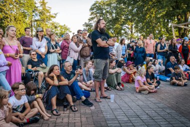 Çocuklar ve yetişkinler de dahil olmak üzere çeşitli insanlar kültürel performansı dikkatle izliyorlar.. 