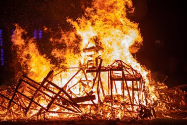 Ahşap yapı gece boyunca tamamen alevlerle kaplıydı. Şiddetli ateş tüm kareyi yutar ve yangının yıkıcı gücünü vurgular..