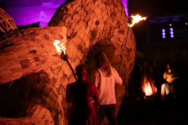 stock image  Human figures with lighted torches stand by an illuminated geodesic dome installation, and at night smoke rises from a wooden sphere.