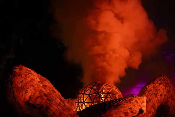 stock image In the wooden sculptures in Valmiermuia park. The wooden dome emits smoke and glows with a warm light at night.