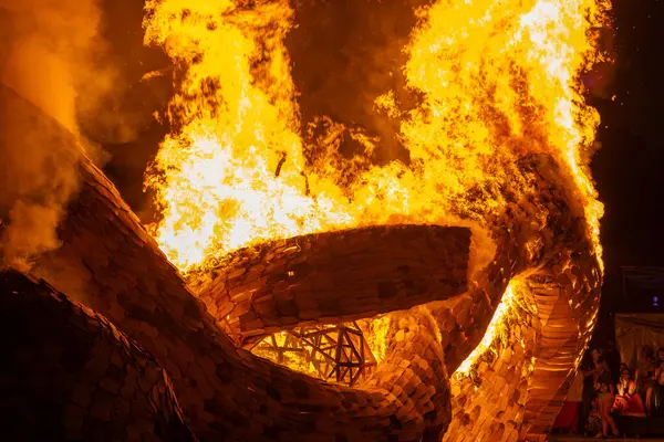 stock image A wooden sculpture with a wooden fireball, intense flames and thick smoke. The burning wood contrasts with the bright flames, highlighting the destructive power of fire.