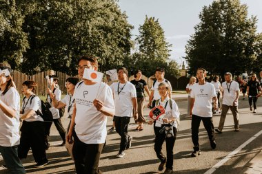 Bir grup insan, canlı bir şehir ortamında mesajlarını ifade eden pankartlar taşıyan bir şehir festivaline katılıyor. Sahne, arka planda çeşitli bir kalabalıkla festivalin enerji ve nişanını yakalıyor..