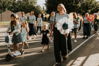 Bir grup insan, canlı bir şehir ortamında mesajlarını ifade eden pankartlar taşıyan bir şehir festivaline katılıyor. Sahne, arka planda çeşitli bir kalabalıkla festivalin enerji ve nişanını yakalıyor..