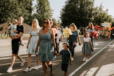 Bir grup insan, canlı bir şehir ortamında mesajlarını ifade eden pankartlar taşıyan bir şehir festivaline katılıyor. Sahne, arka planda çeşitli bir kalabalıkla festivalin enerji ve nişanını yakalıyor..