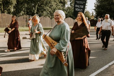 Bir grup insan, canlı bir şehir ortamında mesajlarını ifade eden pankartlar taşıyan bir şehir festivaline katılıyor. Sahne, arka planda çeşitli bir kalabalıkla festivalin enerji ve nişanını yakalıyor.. 