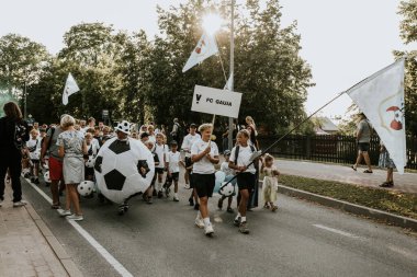 Bir grup insan, canlı bir şehir ortamında mesajlarını ifade eden pankartlar taşıyan bir şehir festivaline katılıyor. Sahne, arka planda çeşitli bir kalabalıkla festivalin enerji ve nişanını yakalıyor.. 