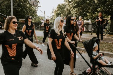 Bir grup insan, canlı bir şehir ortamında mesajlarını ifade eden pankartlar taşıyan bir şehir festivaline katılıyor. Sahne, arka planda çeşitli bir kalabalıkla festivalin enerji ve nişanını yakalıyor.. 