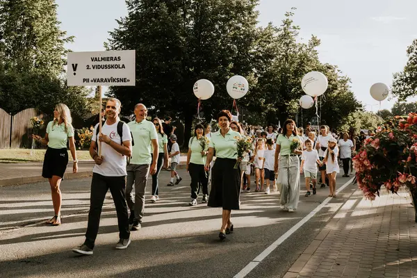 Bir grup insan, canlı bir şehir ortamında mesajlarını ifade eden pankartlar taşıyan bir şehir festivaline katılıyor. Sahne, arka planda çeşitli bir kalabalıkla festivalin enerji ve nişanını yakalıyor..