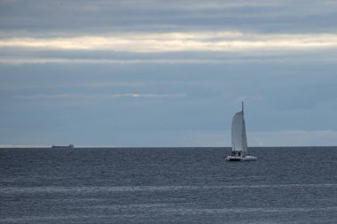 Sakin bir denizde yüzen bir teknenin sakin bir görüntüsü, ufukta ufuk çizgisi olan açık suların dinginliğini ve enginliğini yakalıyor..