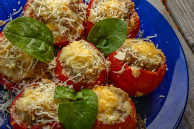 Baharatlı karışımla doldurulmuş, erimiş peynir ve ıspanak yapraklarıyla kaplanmış domateslerin yakın çekimi. Domatesler kızarana kadar kızarır..