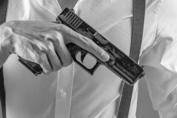 Beyaz tişörtlü bir adamın tabancasını kaldırırken ve silahı odaklanmış bir şekilde tutarken yakın plan fotoğrafı. Arkaplan tarafsız, kopyalama alanı sağlıyor.