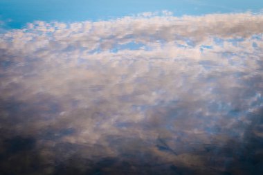 Sakin sulardaki bulutların yumuşak, bulanık bir yansıması soyut ve barışçıl bir görüntü yaratıyor. Sessiz maviler ve gri tonların karışımı sakin, rüya gibi bir atmosfer yaratır..