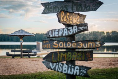 A wooden post with hand-painted signs pointing to various destinations, including 