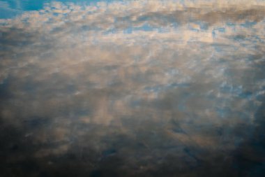Sakin sulardaki bulutların yumuşak, bulanık bir yansıması soyut ve barışçıl bir görüntü yaratıyor. Sessiz maviler ve gri tonların karışımı sakin, rüya gibi bir atmosfer yaratır..